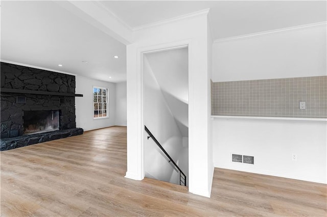 unfurnished living room with crown molding, visible vents, a fireplace, and wood finished floors