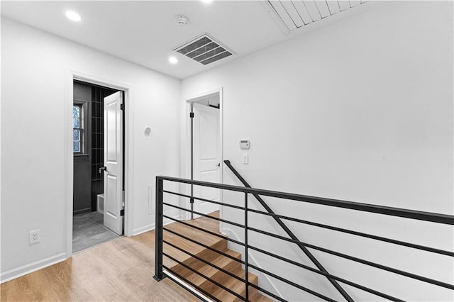 corridor with light wood-style flooring, recessed lighting, an upstairs landing, baseboards, and visible vents