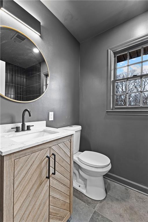 half bath featuring toilet, visible vents, and vanity