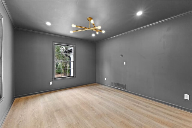 empty room with visible vents, crown molding, and wood finished floors