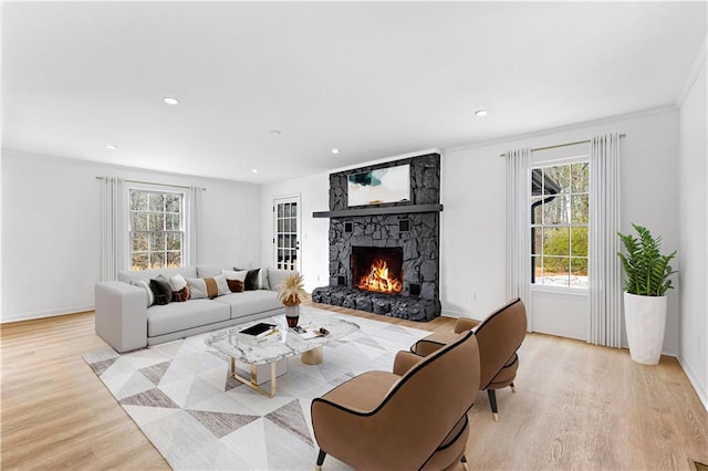 living room with light wood-style floors, a fireplace, crown molding, and recessed lighting