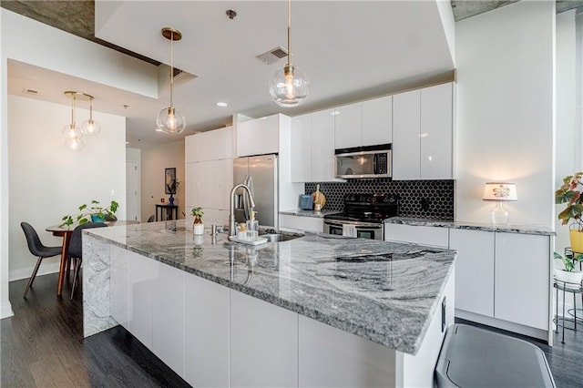 kitchen featuring stainless steel appliances, visible vents, decorative backsplash, white cabinets, and a sink