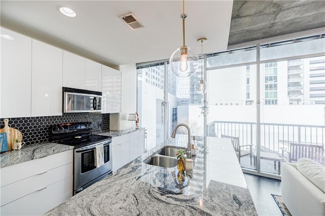 kitchen featuring visible vents, decorative backsplash, appliances with stainless steel finishes, floor to ceiling windows, and a sink