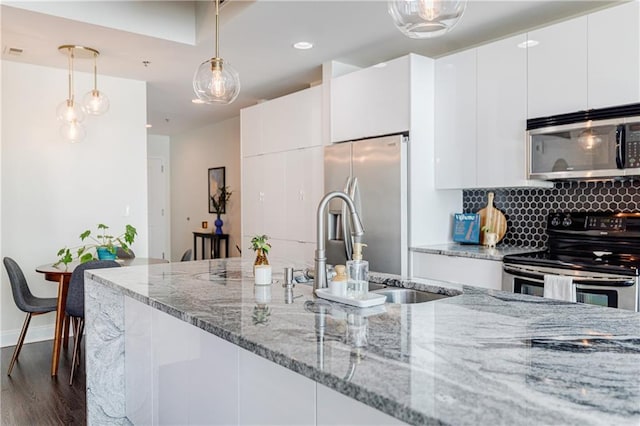 kitchen with dark wood-style floors, appliances with stainless steel finishes, white cabinets, and backsplash