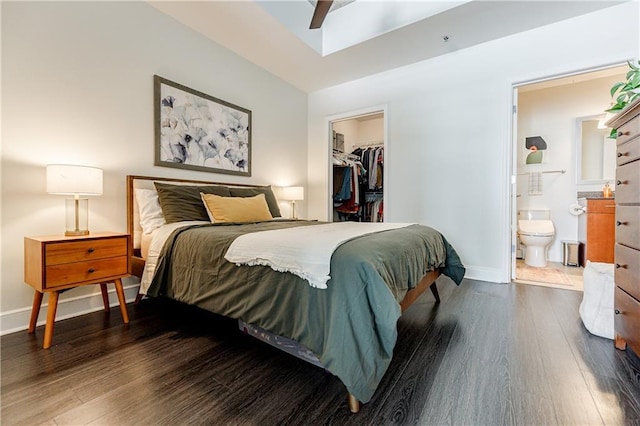 bedroom with a closet, a spacious closet, connected bathroom, wood finished floors, and baseboards