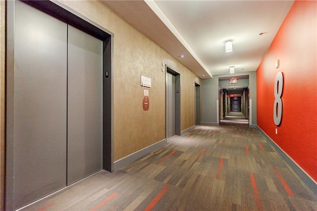 hallway featuring baseboards and elevator