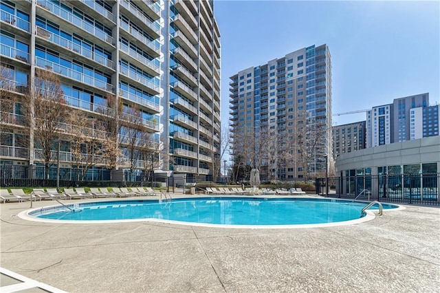 pool with fence, a city view, and a patio