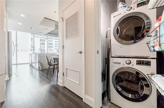 laundry room featuring stacked washer and dryer, recessed lighting, visible vents, wood finished floors, and laundry area