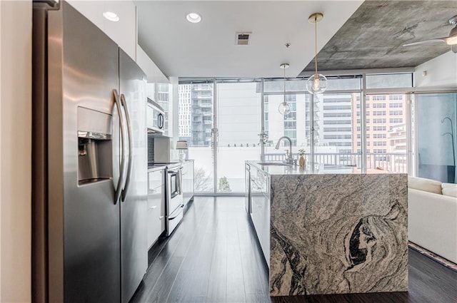 kitchen with appliances with stainless steel finishes, dark wood-type flooring, a sink, and white cabinets