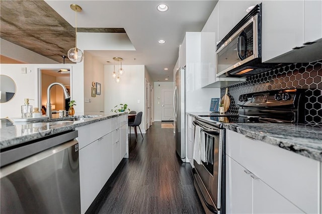 kitchen with dark wood-style flooring, decorative backsplash, appliances with stainless steel finishes, white cabinets, and a sink