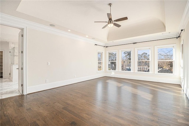 empty room featuring ceiling fan, dark hardwood / wood-style flooring, crown molding, and a tray ceiling