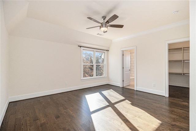 unfurnished bedroom featuring ceiling fan, dark hardwood / wood-style flooring, a spacious closet, and ensuite bath