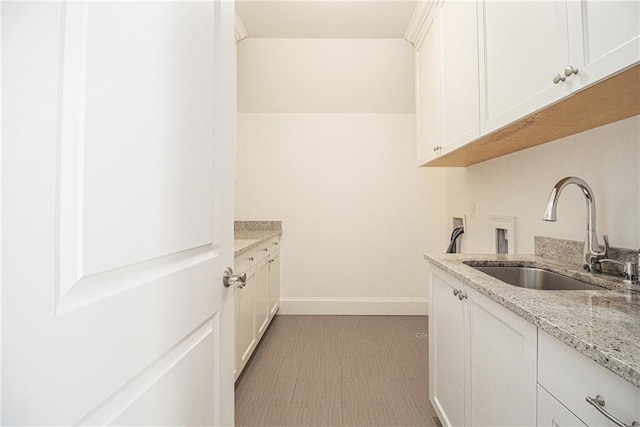 kitchen featuring white cabinetry, sink, and light stone counters