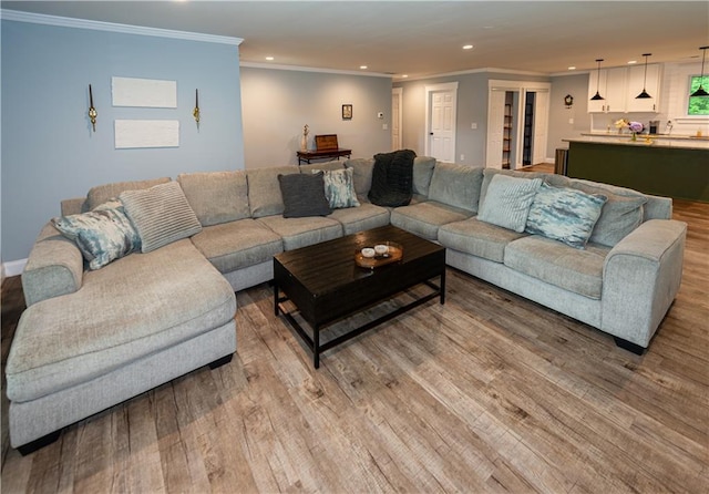 living area with crown molding, recessed lighting, and light wood-style floors