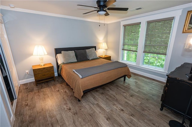bedroom featuring ceiling fan, visible vents, crown molding, wood finished floors, and baseboards