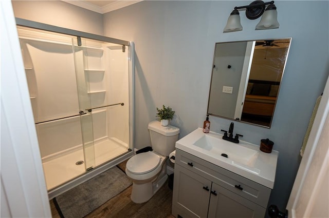 bathroom featuring toilet, ornamental molding, wood finished floors, and a stall shower