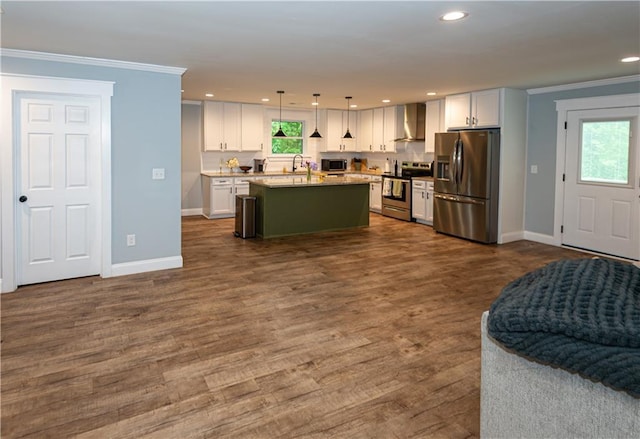 kitchen with appliances with stainless steel finishes, ornamental molding, wall chimney exhaust hood, and open floor plan