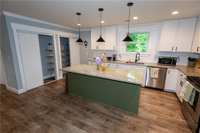 kitchen featuring crown molding, white cabinets, a sink, stainless steel appliances, and tasteful backsplash