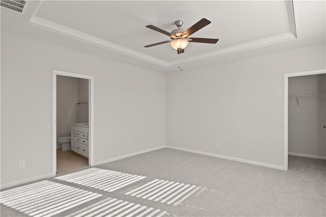 488 Village Ln, Fairburn, GA 30213 - unfurnished bedroom with a tray ceiling, light colored carpet, a walk in closet, a closet, and baseboards