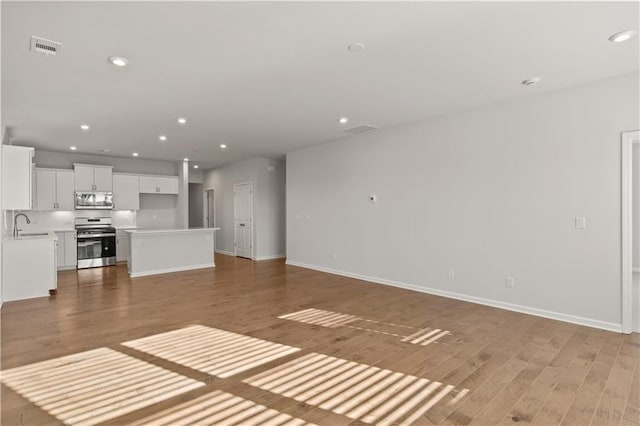 488 Village Ln, Fairburn, GA 30213 - unfurnished living room with light wood-style flooring, recessed lighting, baseboards, and a sink