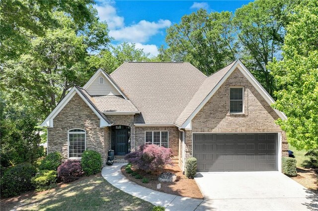 craftsman-style house with stone siding, a shingled roof, brick siding, and concrete driveway