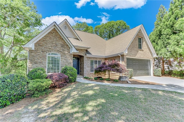 view of front of property with a front lawn, driveway, stone siding, an attached garage, and a shingled roof