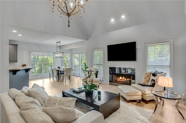 living room with light wood-type flooring, a wealth of natural light, a notable chandelier, and recessed lighting