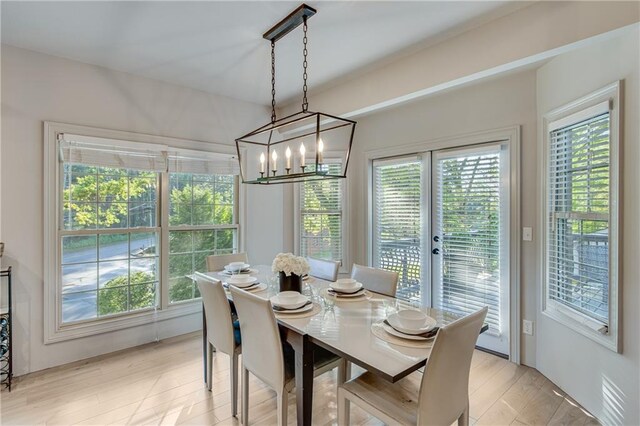 dining room featuring a notable chandelier, french doors, light wood finished floors, and plenty of natural light