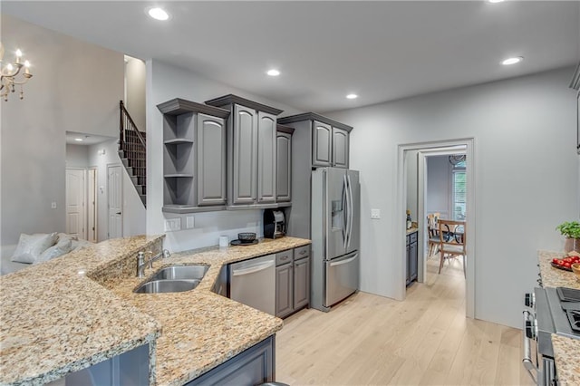 kitchen featuring stainless steel appliances, a peninsula, light wood-style flooring, a sink, and open shelves