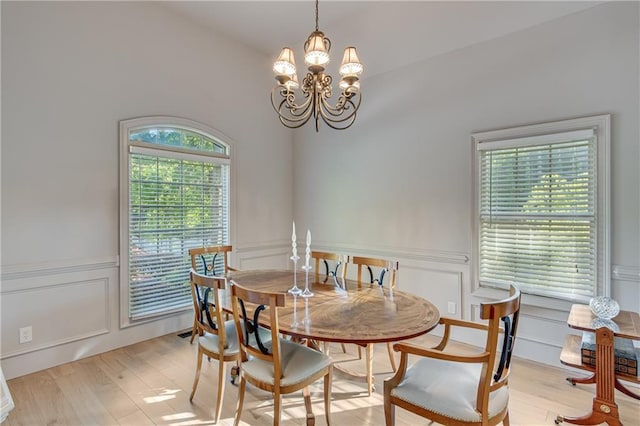 dining space featuring a decorative wall, a chandelier, and light wood finished floors