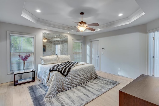 bedroom featuring multiple windows, ornamental molding, and a tray ceiling