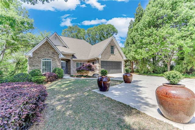 craftsman-style home featuring concrete driveway, an attached garage, stone siding, roof with shingles, and a front yard