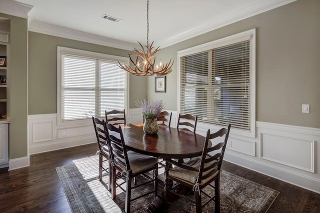 dining area with dark hardwood / wood-style floors, crown molding, and a notable chandelier