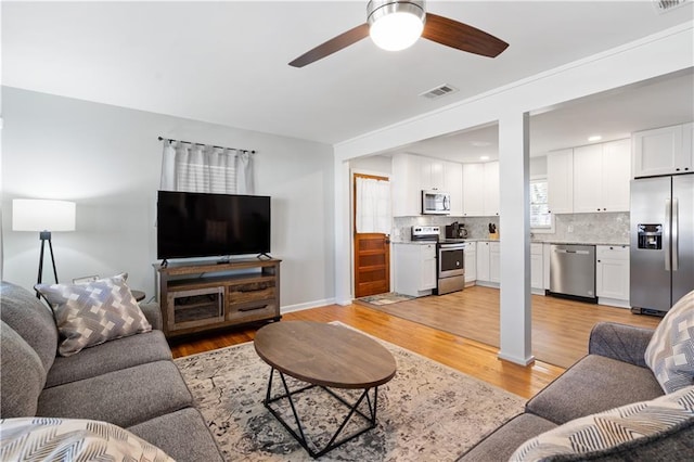 living room with light hardwood / wood-style flooring and ceiling fan