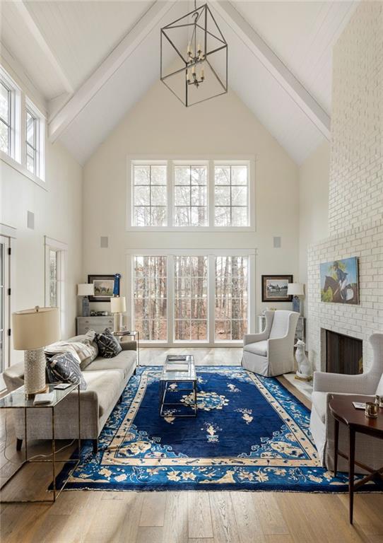 9229 Selborne Ln, Chattahoochee Hills, GA 30268 - living room featuring high vaulted ceiling, wood finished floors, a chandelier, beamed ceiling, and a fireplace