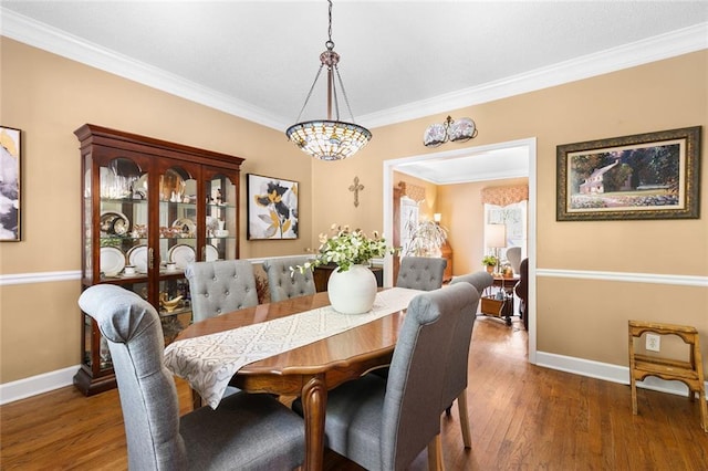 dining space with baseboards, crown molding, and wood finished floors