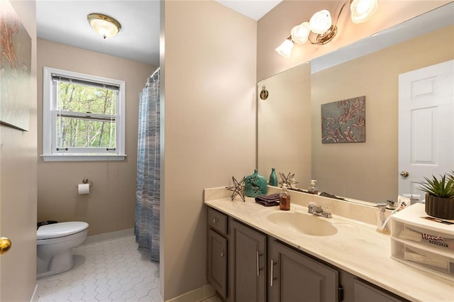 full bath featuring vanity, baseboards, tile patterned floors, and toilet