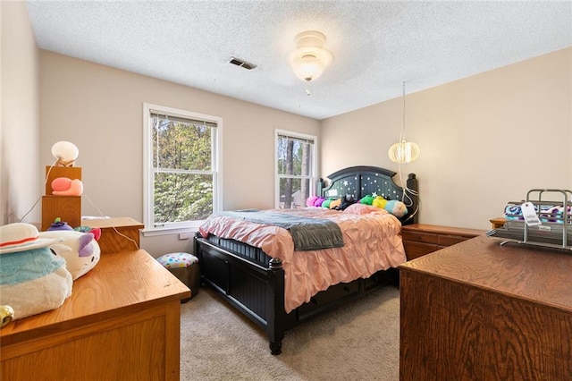 bedroom with light carpet, a textured ceiling, and visible vents