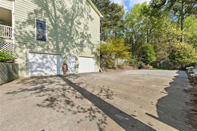 view of property exterior with a garage, aphalt driveway, and fence
