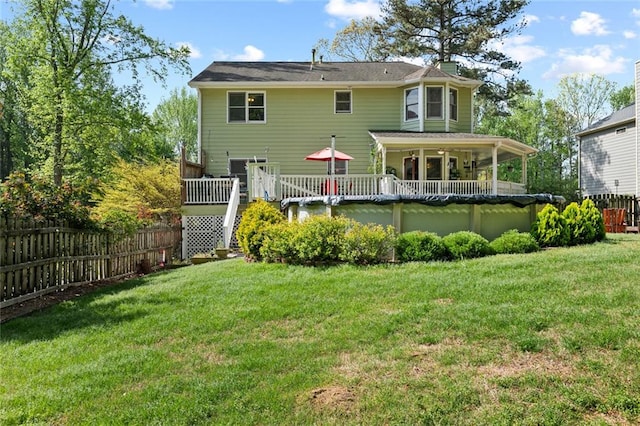 back of property with a lawn, a deck, fence, and a chimney