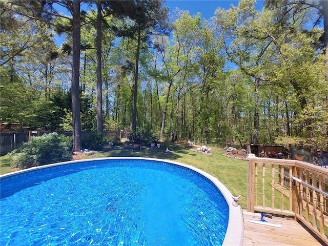 pool with a fenced backyard, a wooden deck, and a yard