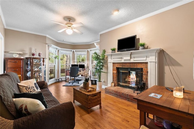 living room featuring crown molding, a brick fireplace, wood finished floors, a textured ceiling, and a ceiling fan