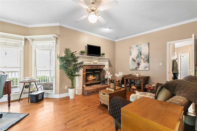 living area featuring ornamental molding, a brick fireplace, light wood-style floors, ceiling fan, and a textured ceiling