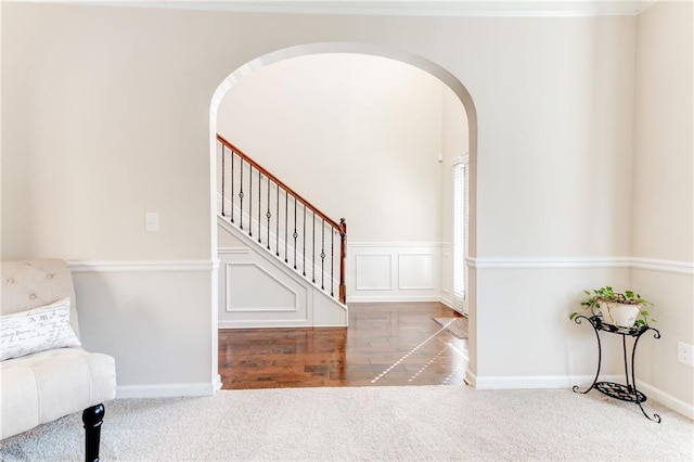 interior space with arched walkways, a decorative wall, baseboards, and stairs