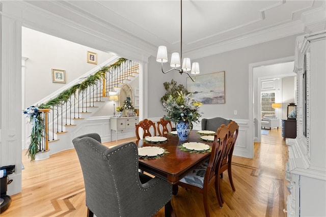 dining area with light wood-type flooring, a notable chandelier, and ornamental molding