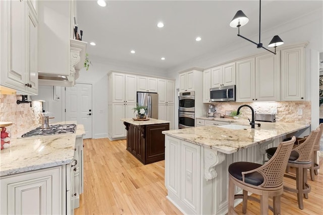 kitchen with white cabinets, sink, hanging light fixtures, and appliances with stainless steel finishes