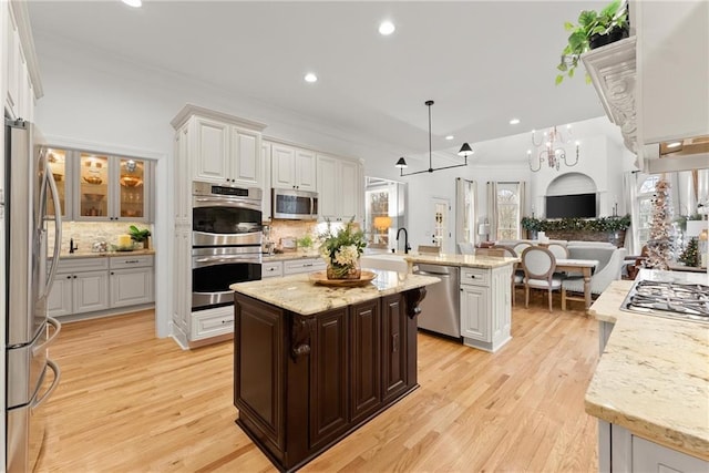 kitchen with decorative backsplash, decorative light fixtures, a kitchen island, stainless steel appliances, and a chandelier