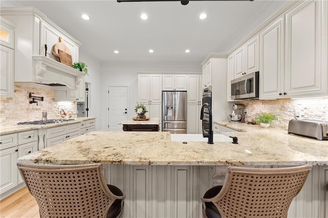 kitchen featuring backsplash, white cabinetry, a breakfast bar, and stainless steel appliances