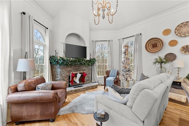 living room with a fireplace, ornamental molding, light wood-type flooring, and a notable chandelier