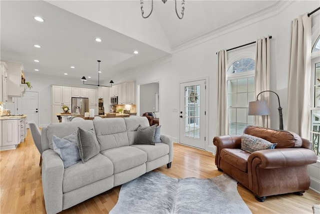 living room featuring light wood-type flooring, an inviting chandelier, and lofted ceiling